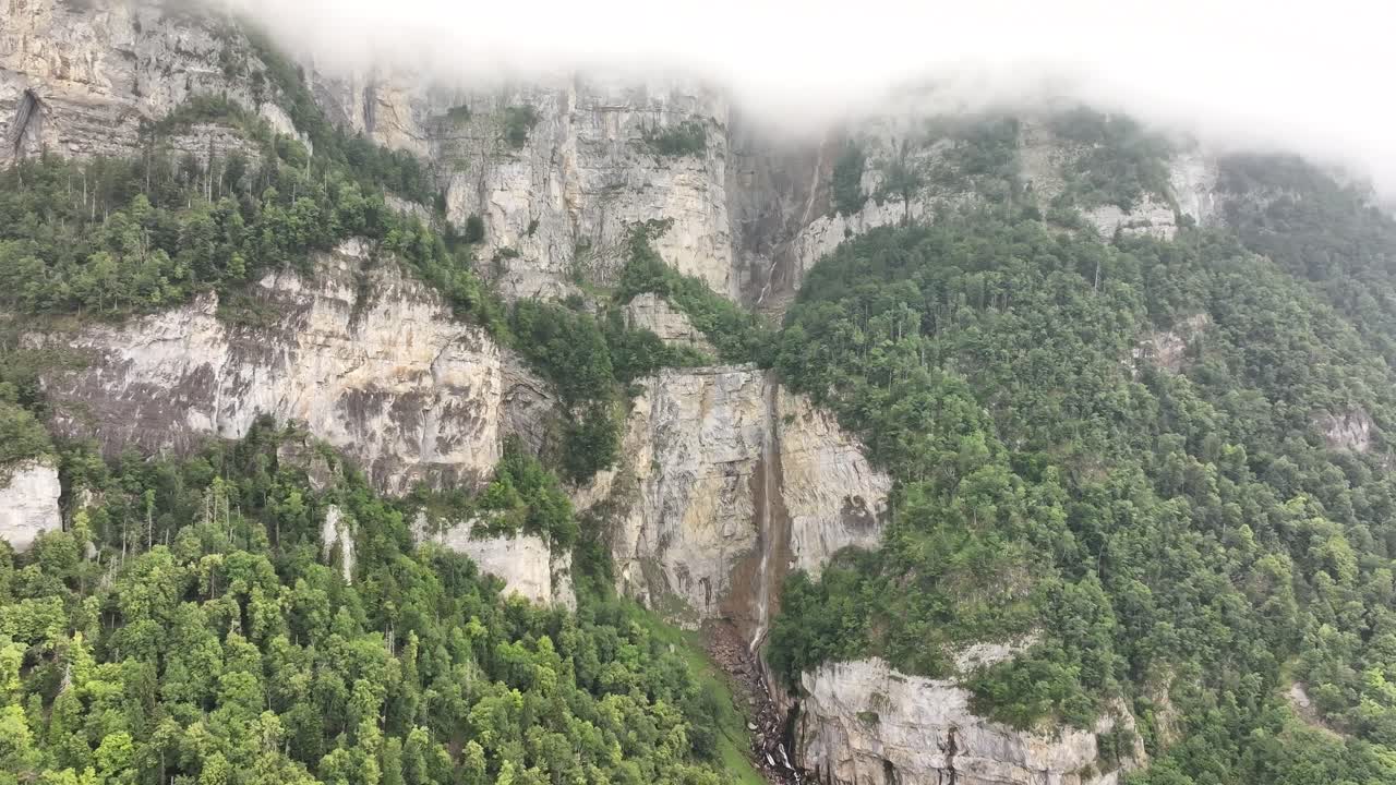 Seerenbachfälle waterfall at Walensee, Amden Betlis, Switzerland, aerial drone pull-back view, tall cliff falls in green mountains and misty clouds