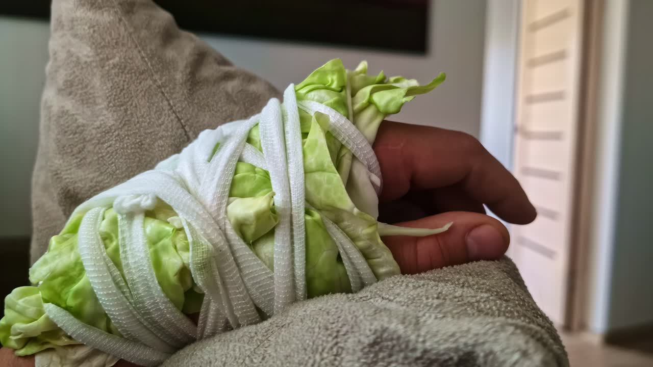 Close view of a hand wrapped in lettuce, homemade healing device, east Europe healing technique