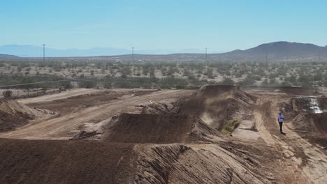 Motorcycle-approaches-a-dirt-ramp-and-makes-a-long-and-high-jump-towards-the-drone