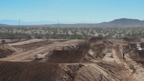 la motocicleta se acerca a una rampa de tierra y da un salto largo y alto hacia el dron