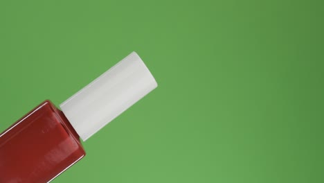 diagonal rotation of a glass bottle of nail polish. isolated on green.