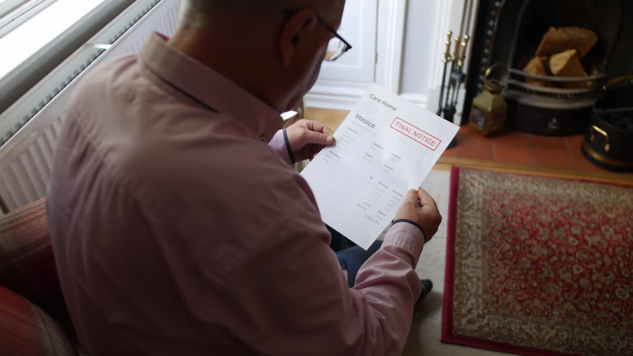 un anciano solitario abriendo una carta de deuda