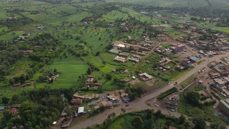 bird's eye view of countryside road between green fields and trees in the rural town of loitokitok in kenya - aerial drone shot