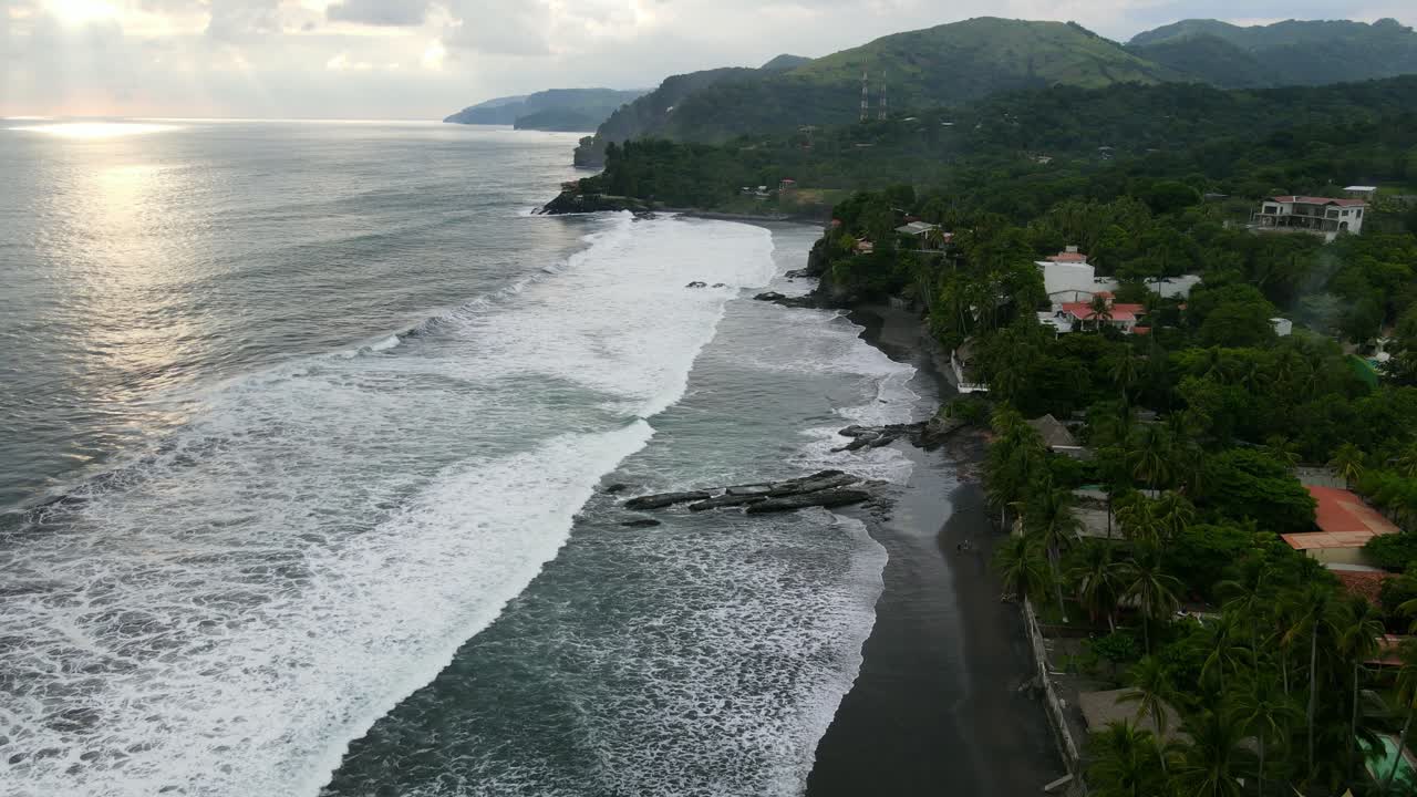 vista aérea que avanza, vista panorámica de la luz del sol que se refleja en la playa en bitcoin beach en el salvador, méxico, montaña y cielo azul en el fondo