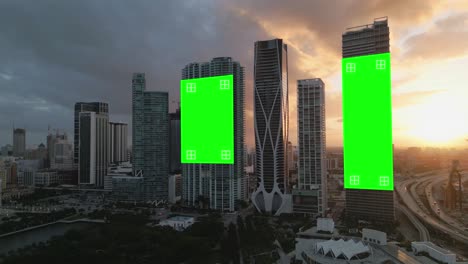 Aerial-established-of-smart-city-modern-skyline-at-sunset-with-empty-billboard-green-screen-with-tracking-markers