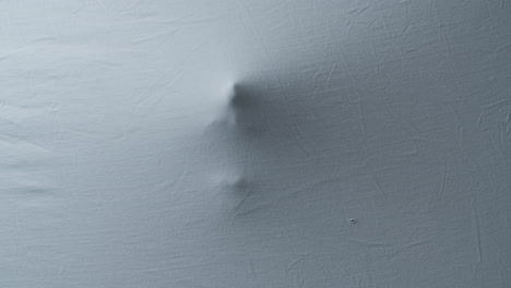 close up shot of a creepy head pressing against a bedsheet