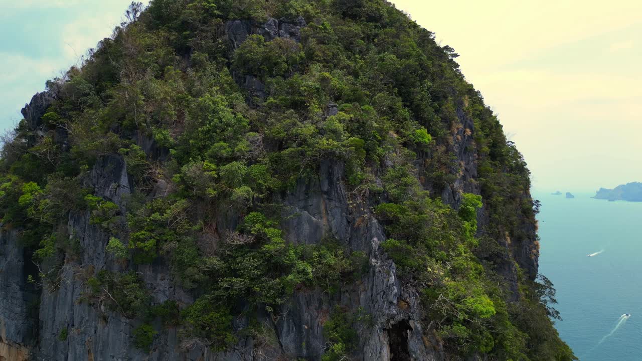 Rock climber resting during a difficult climb on Rai Leh beach cliff in Thailand. Great aerial view flight descending drone