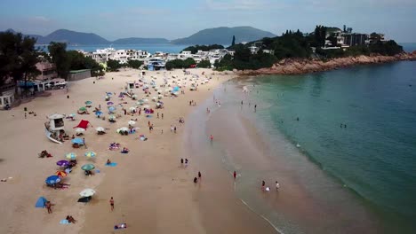 Vista-Aérea-En-Movimiento-De-180-Grados-De-Los-Visitantes-En-La-Playa-De-Shek-O-En-Hong-Kong-Mientras-Las-Playas-Públicas-Reabren,-Después-De-Meses-De-Cierre-En-Medio-Del-Brote-De-Coronavirus,-Al-Público