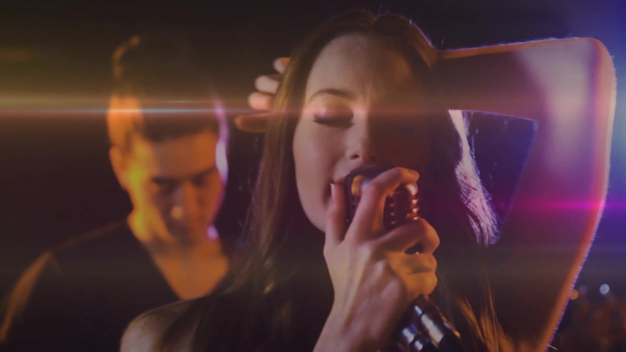 Cantante donna che porta un microfono vintage alla bocca, cantando musica mentre bagliori dell'obiettivo attraversano il viso.