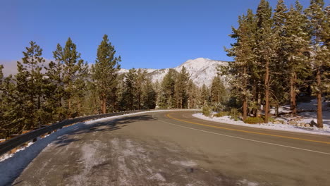 Autos-Fahren-Auf-Einer-Bergstraße-Vorbei,-Während-Die-Kamera-Hochfährt,-Um-Berge-Und-Blauen-Himmel-Am-Horizont-In-Lake-Tahoe,-Nevada,-Zu-Enthüllen