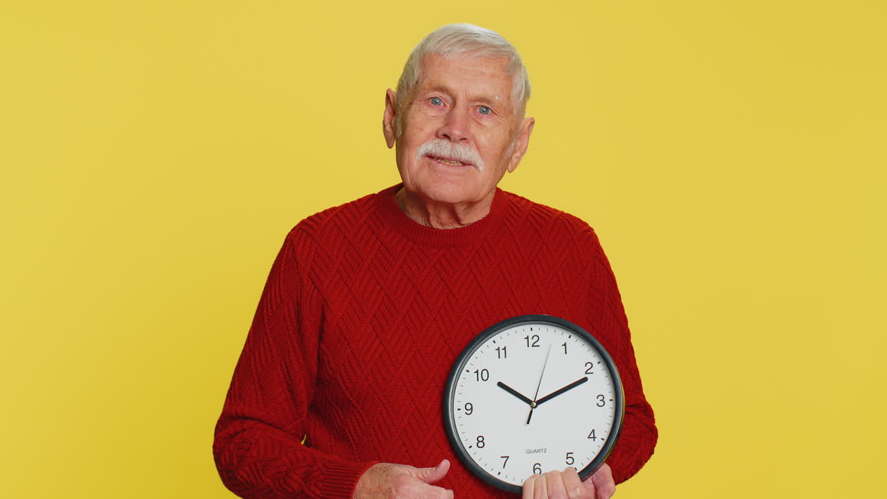 Vecchio anziano che mostra l'ora sull'orologio da ufficio a parete ok pollice in alto approva sbrigati scadenza