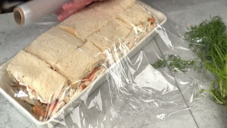 preparación de comida de primer plano: envoltura de plástico agregada al pastel de sándwich smorgastarta