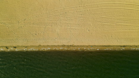 aerial top-down view from the high altitude of piedras river waves rolling over sandy beach coastline when few undecognizable people standing waterfront