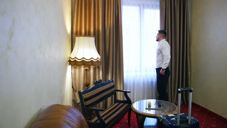 young handsome man relaxing at his apartment in a hotel after business meeting. booking hotel during vacation. businessman in luxury room of the expensive beautiful hotel.