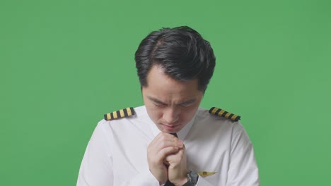 close up of asian man pilot praying for something while standing in the green screen background studio