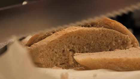 Weibliche-Hand,-Die-Das-Letzte-Stück-Frisch-Gebackenes-Sauerteigbrot-Mit-Einem-Scharfen-Brotmesser-Durchschneidet,-Bevor-Sie-Zur-Seite-Gelegt-Wird