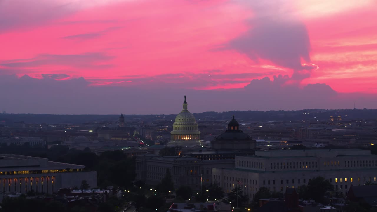 Ripresa con drone al tramonto del Campidoglio degli Stati Uniti con la sua cupola illuminata, circondato da edifici cittadini sotto un cielo vibrante