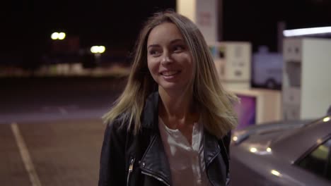 Romantic,-Smiling-Woman-At-The-Gas-Station-In-Caual,-The-Car-In-The-Background-Walks-And-Posing