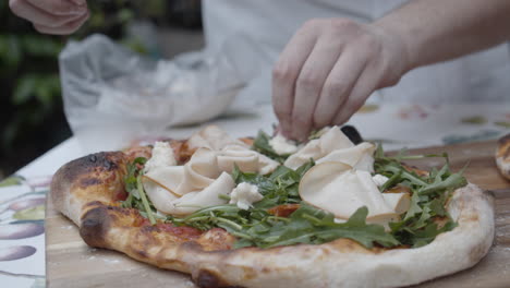 chef puts topping onto neapolitan pizza