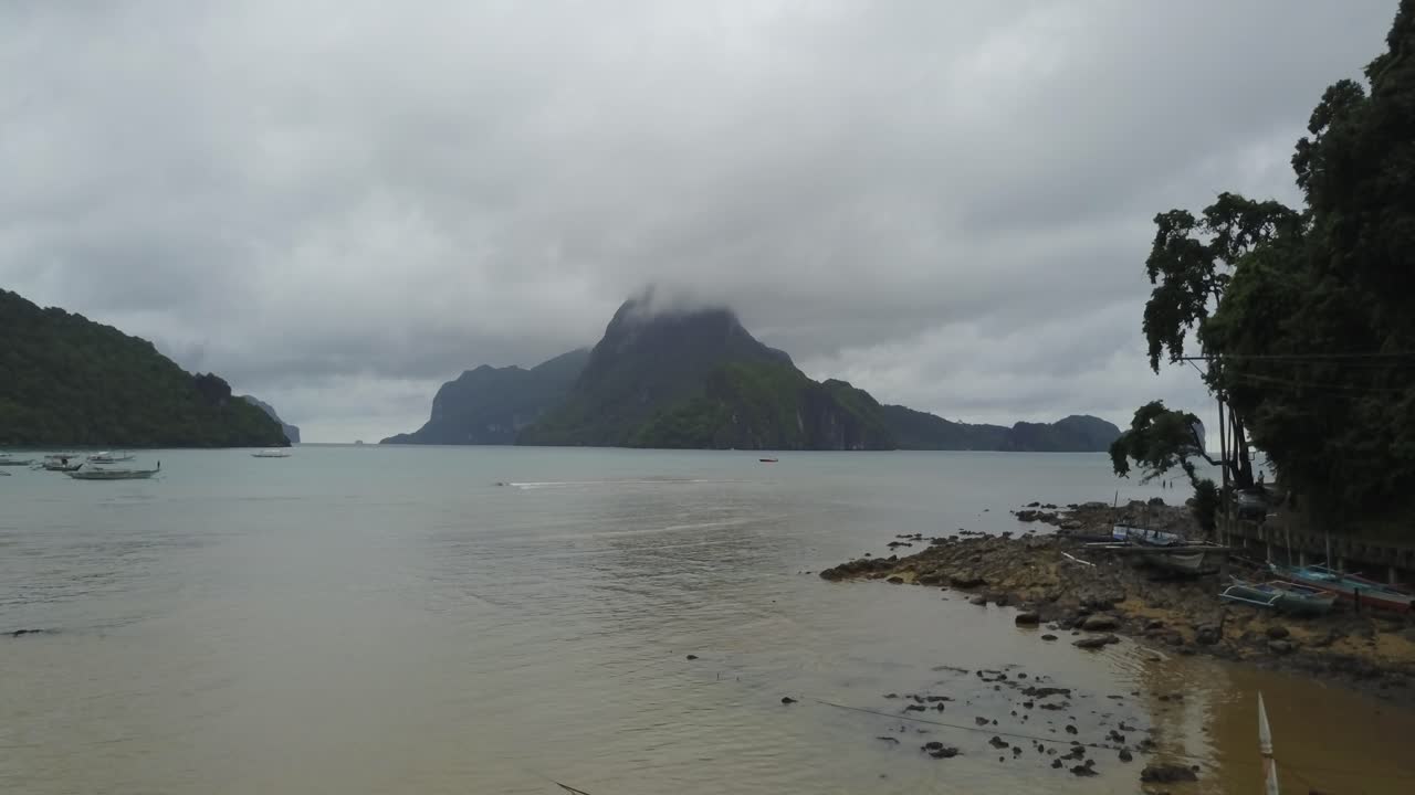 Quang cảnh từ trên không ở độ cao thấp bay về phía trước qua vịnh nhiệt đới với những chiếc thuyền truyền thống và đảo đá vôi ở El Nido, Palawan, Philippines