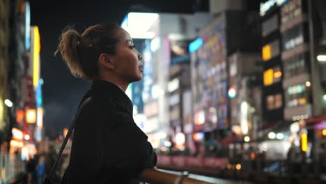 lady in black gazes over an urban landscape at night