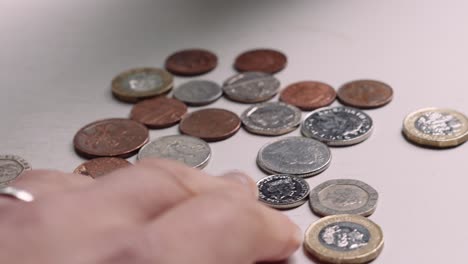 persona pobre contando a mano una pequeña cantidad de dinero que queda en monedas británicas