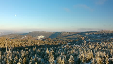 wide aerial view on a sunny day of a scenic rural landscape, dolly forward, the moon is visible on the left side, black forest, germany