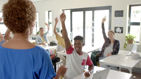 in high school, students raising hands to answer teacher's question in classroom