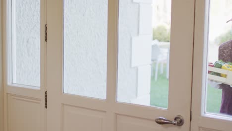 delivery man wearing face mask with groceries knocking at the door