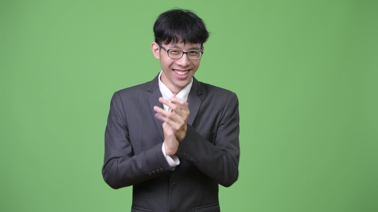 기쁜 젊은 아시아 사업가 가 손을 치면서 미소 짓고 있다