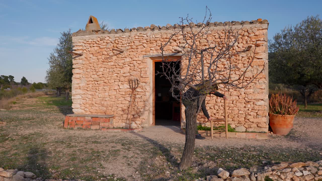 antigua casa de piedra en medio de olivares mediterráneos, un hombre prepara la mesa para el almuerzo a principios de la primavera