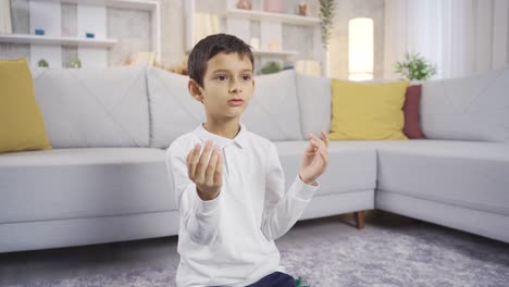 muslim boy praying at home with open hands.