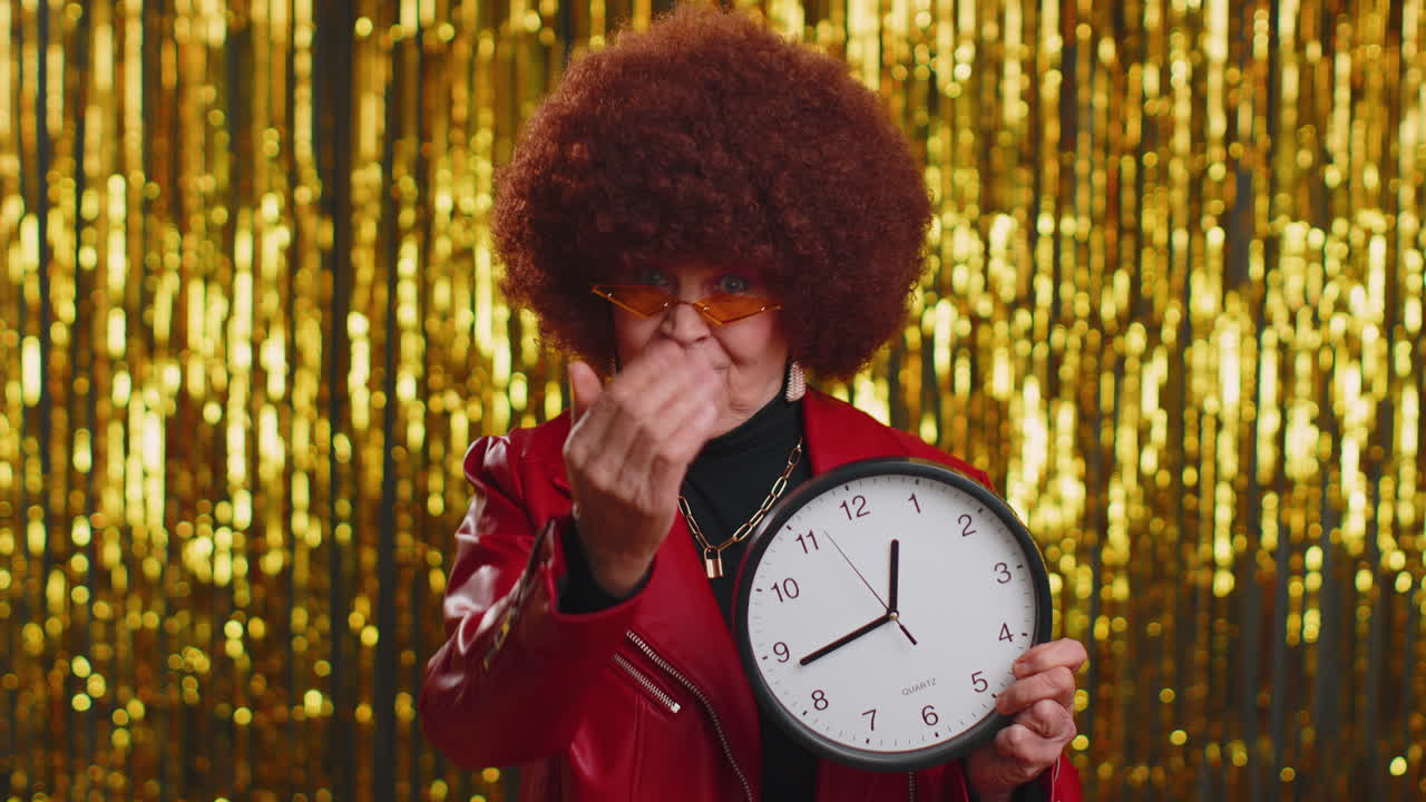 mujer mayor con estilo que muestra el tiempo en el reloj, ok, pulgar hacia arriba, aprobar, señalando con el dedo a la cámara