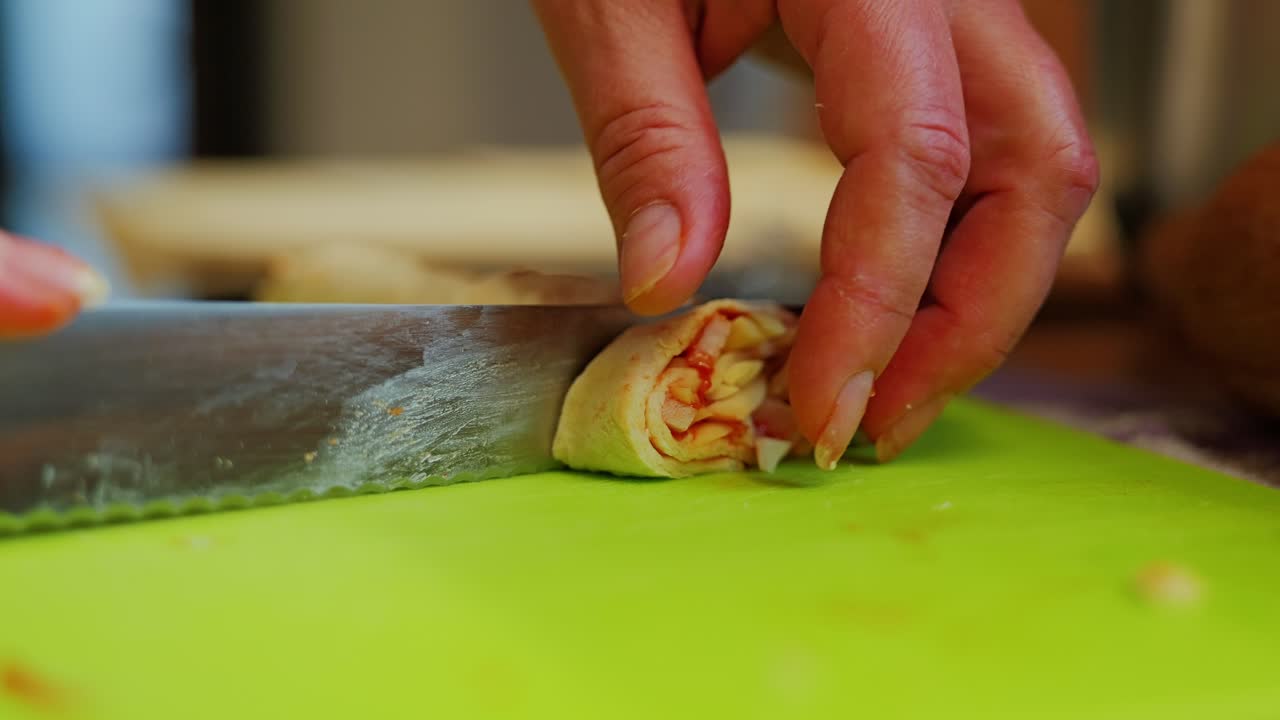 Home cooking moment slicing savory dough roll with cheese and ham inside