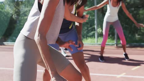 Happy-diverse-female-basketball-team-training-with-male-coach-on-sunny-court,-in-slow-motion