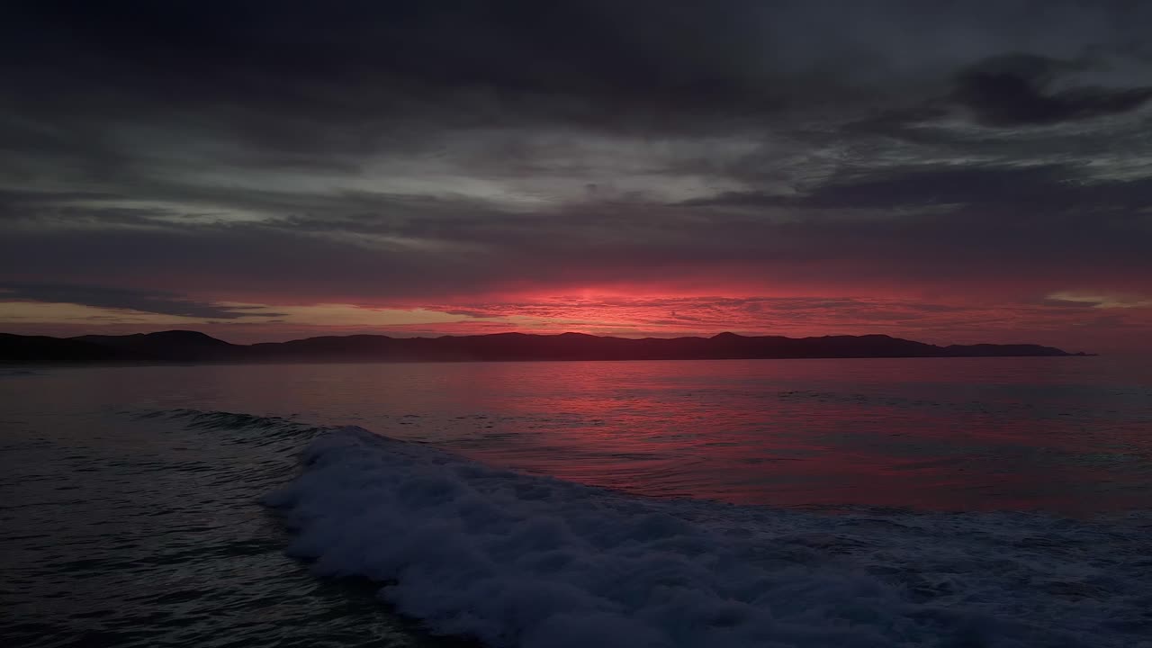 Dramatisk solnedgangshimmel og havbølger i Spirits Bay, New Zealand - dronestatik