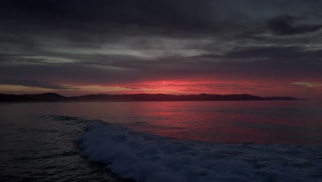 dramatic sunset sky and ocean waves in spirits bay, new zealand - drone static