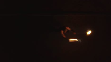 joven hombre rubio hace baile de fuego con dos antorchas gira antorchas en llamas aéreas