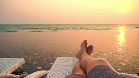 Punto-De-Vista-Personal-Del-Hombre-Acostado-En-La-Cama-De-La-Piscina-Infinita,-Mirando-Las-Olas-Del-Mar-Bajo-El-Sol