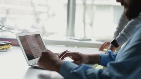 Kollegen-Diskutieren-Geschäftliche-Themen-Und-Zeigen-Auf-Laptop.