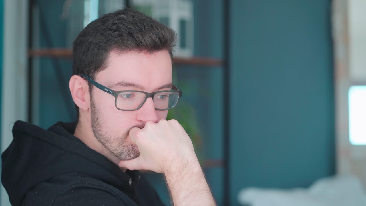 Pensive young man sitting pondering in living room