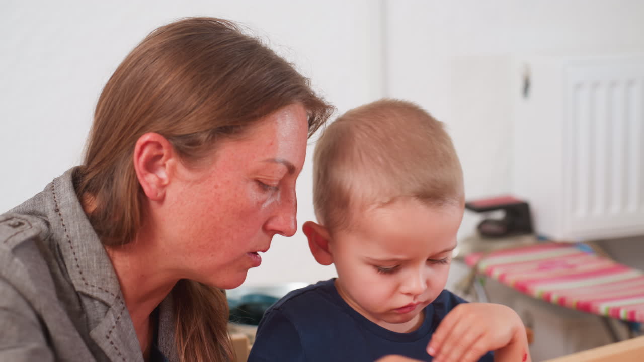 수업 시간에 지루해하는 남자아이를 환자가 코칭하는 클로즈업 장면입니다. 아이는 턱을 손에 괸 채 딴 곳을 보고 있고, 참여도는 낮습니다. 은은한 교실 조명 아래 지원적인 지도가 이루어지고 있습니다.