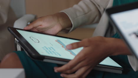 close up hands business woman using digital tablet computer browsing financial graph information on screen brainstorming ideas with colleagues in office meeting