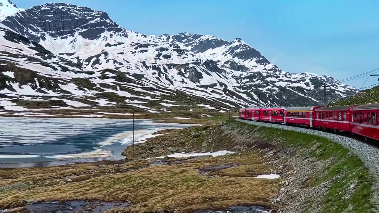 Popular Trem Vermelho do Bernina Express na Ferrovia Rética perto do Lago e dos Alpes Suíços na Suíça. Plano panorâmico.
