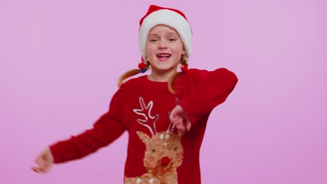 girl in christmas santa sweater hat dancing trendy dance for social media fooling around having fun