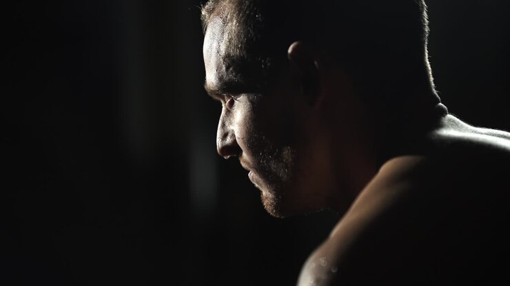 Uomo che respira con rabbia dopo una lotta, sudato, con vene e muscoli tesi