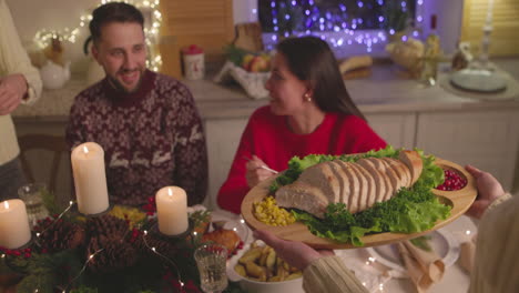 mujer pasando una bandeja con pan rebanado a su amiga durante la cena de navidad