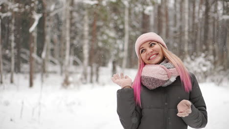 Woman-in-a-jacket-and-hat-in-slow-motion-looks-at-the-snow-and-catches-snowflakes-smiling