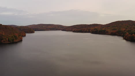 aerial dolly out from the reservoir to the waterfalls - orange tree tops at the new croton dam in westchester county, ny