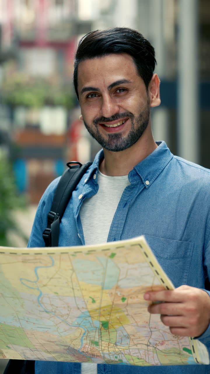 Happy Young Man Looking at Map and Smiling in City